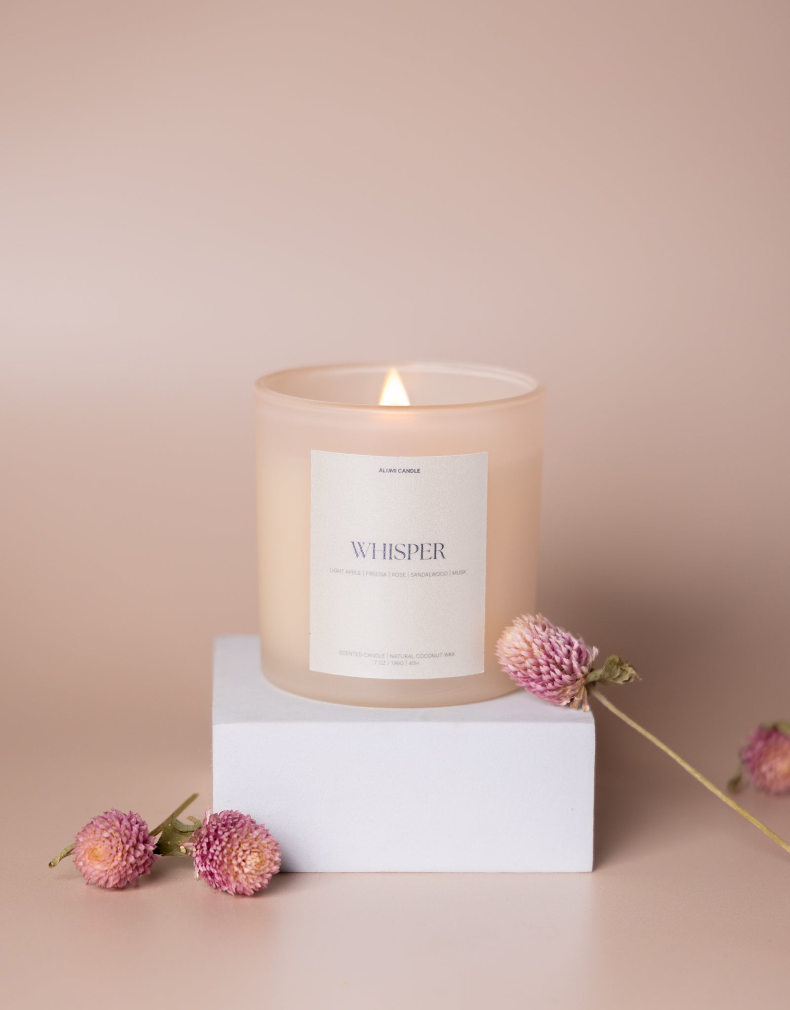 Candle labeled 'Whisper' with flowers on a beige background